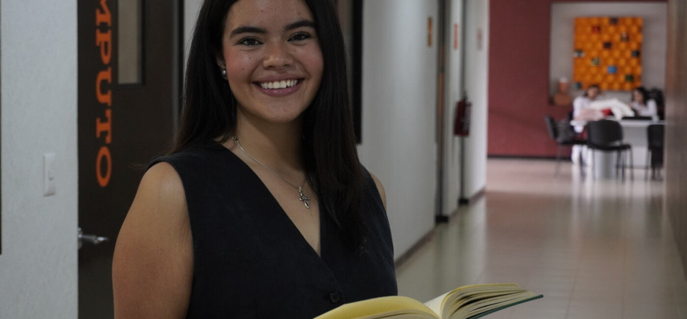 alumna de la anahuac en la biblioteca con un libro 