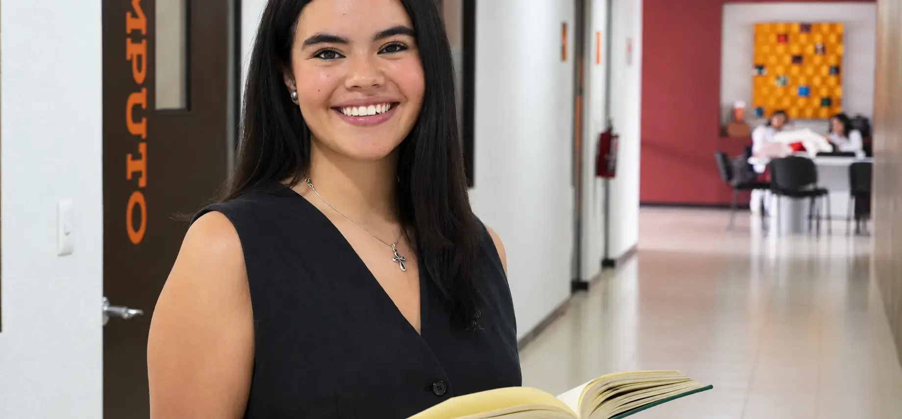 alumna de la anahuac en la biblioteca con un libro 
