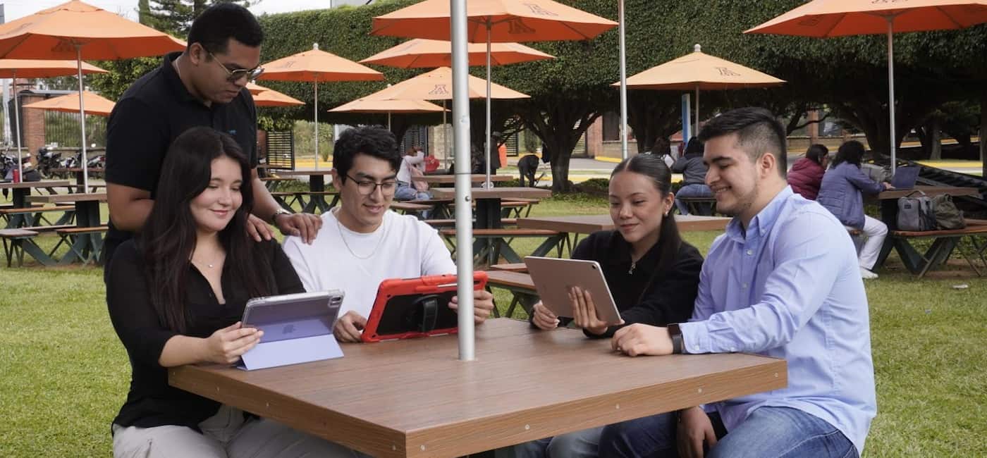 Estudiantes de la Anáhuac Oaxaca en el jardín del campus en una banca colaborando en conjunto