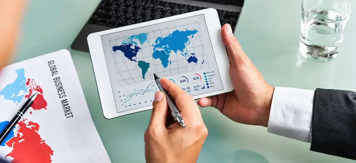 Licenciado en Negocios Internacionales analizando un mapa global y datos en una tableta