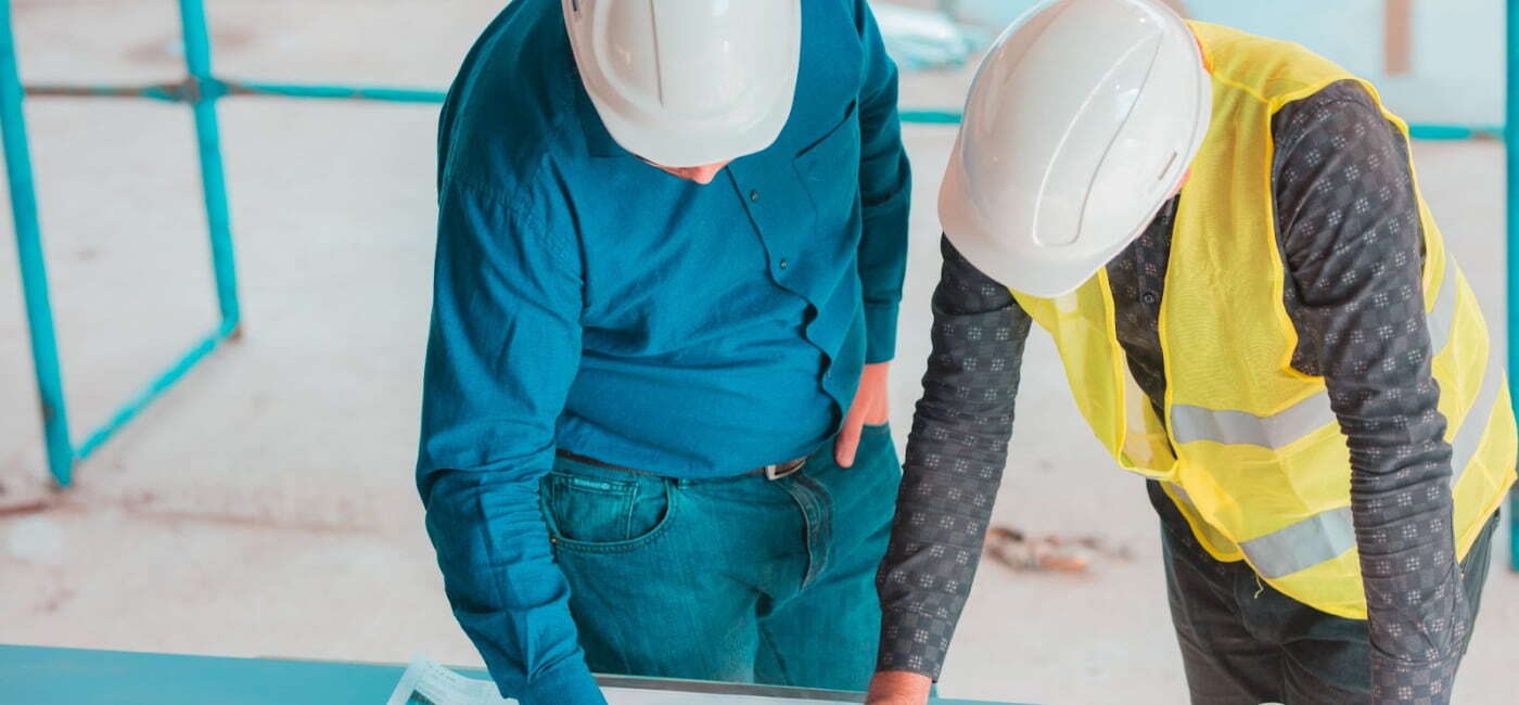Dos ingenieros con casco de seguridad revisando planos en una obra de construcción, ejemplo de carreras con mayor crecimiento en Oaxaca.
