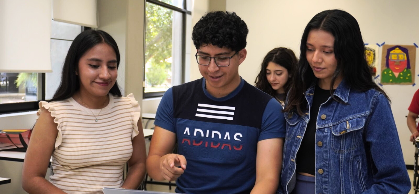 Estudiantes universitarios colaborando en un aula, revisando información en una tablet durante una actividad académica.
