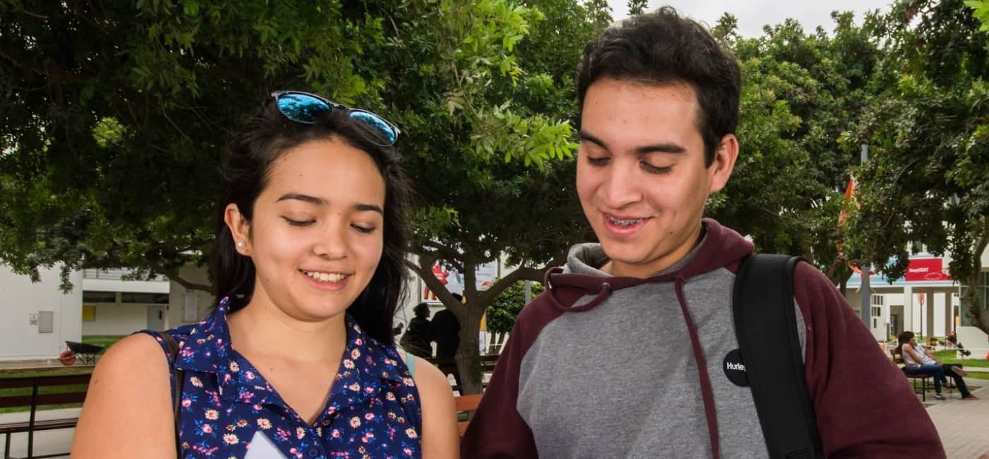 Estudiantes universitarios revisando documentos en campus al aire libre, representando el proceso de adaptación de alumnos foráneos en la Universidad Anáhuac Oaxaca.